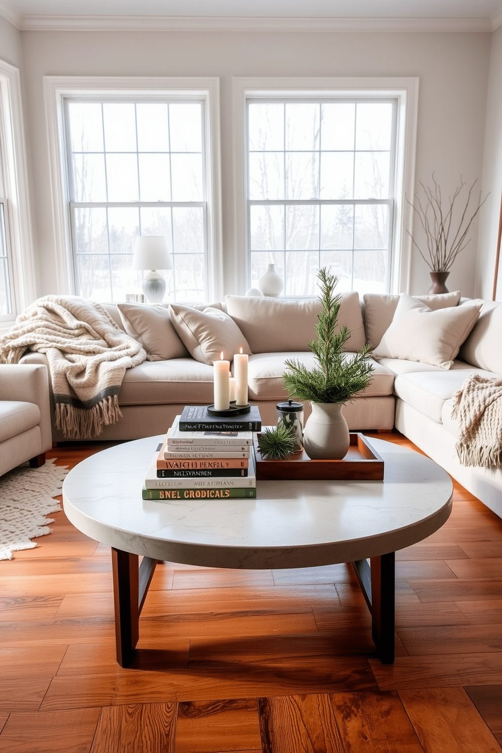 A statement coffee table sits at the center of a cozy winter living room. It is adorned with a stack of art books, a decorative tray with candles, and a small potted evergreen for a touch of nature. The surrounding seating includes a plush sectional sofa draped with soft, textured throws. Large windows allow natural light to flood the space, highlighting the warm tones of the wooden floor and the soft, inviting color palette.