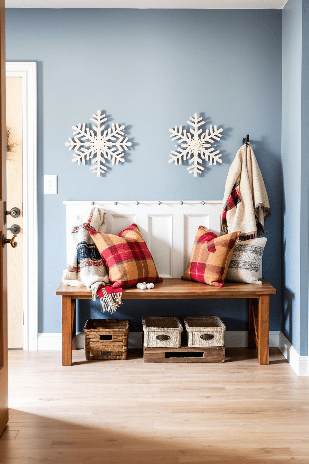 A cozy winter mudroom features decorative snowflake wall art that adds a festive touch to the space. The walls are painted in a soft blue hue, and a rustic wooden bench is placed against one side, adorned with warm blankets and seasonal pillows.