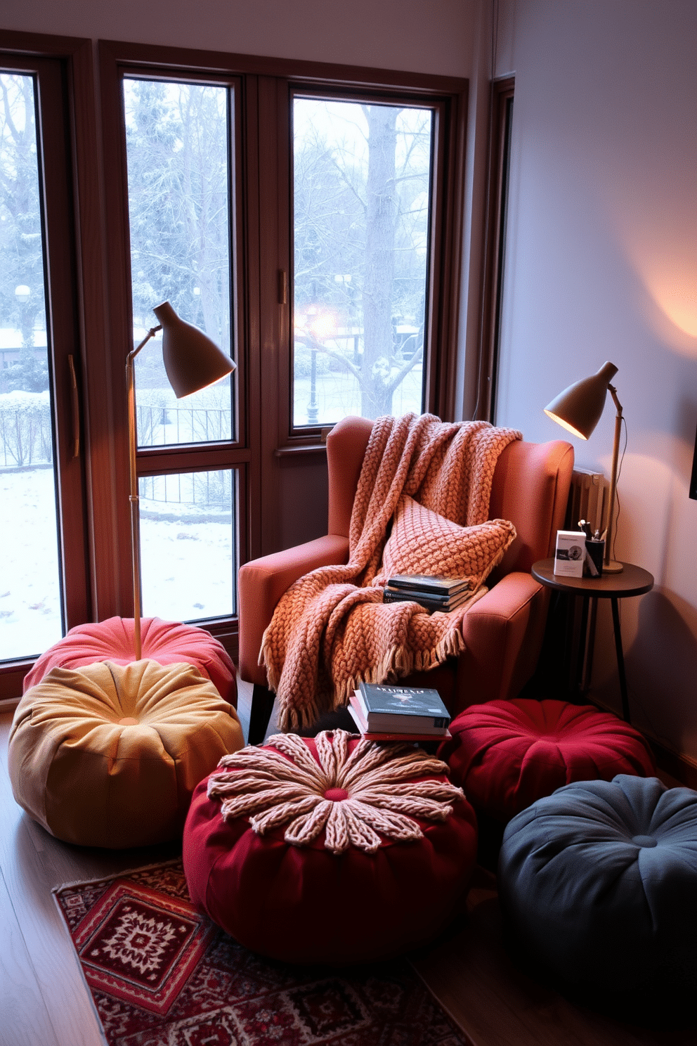 A cozy winter reading nook features a plush armchair draped with a soft knitted blanket. Surrounding the chair are comfortable poufs in varying sizes, providing extra seating and a pop of color. The nook is illuminated by a warm floor lamp, casting a gentle glow over a stack of books on a small side table. A large window offers a view of falling snow, while a rich area rug adds warmth to the space.