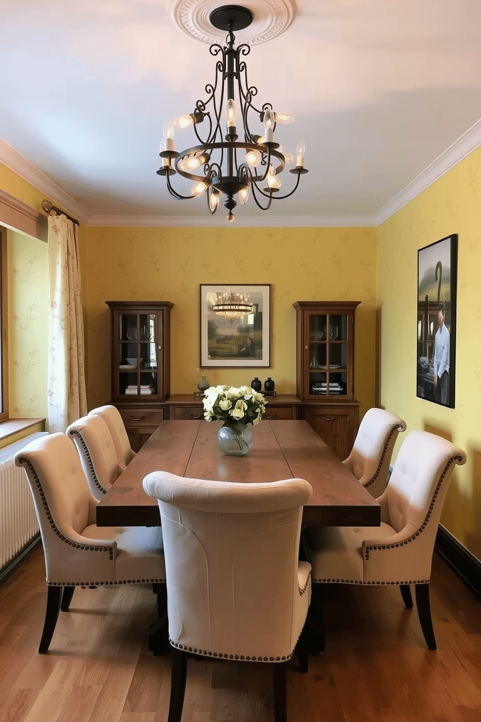 A warm yellow dining room exudes a cozy ambiance, featuring a rustic wooden table surrounded by plush upholstered chairs in soft cream tones. The walls are adorned with subtle floral wallpaper, and a statement chandelier with warm-toned bulbs hangs above, casting a gentle glow over the space.