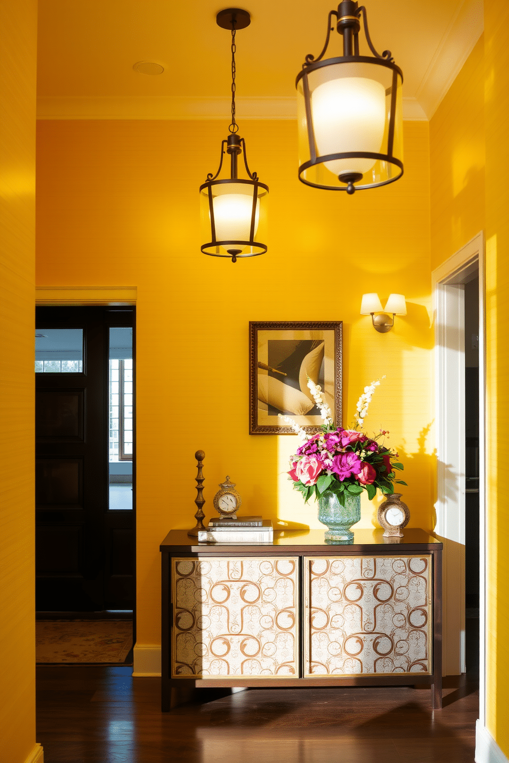 A welcoming foyer bathed in warm yellow light, featuring elegant light fixtures that cast a soft glow throughout the space. The walls are adorned with a subtle textured wallpaper, complemented by a stylish console table topped with decorative accents and a vibrant floral arrangement.