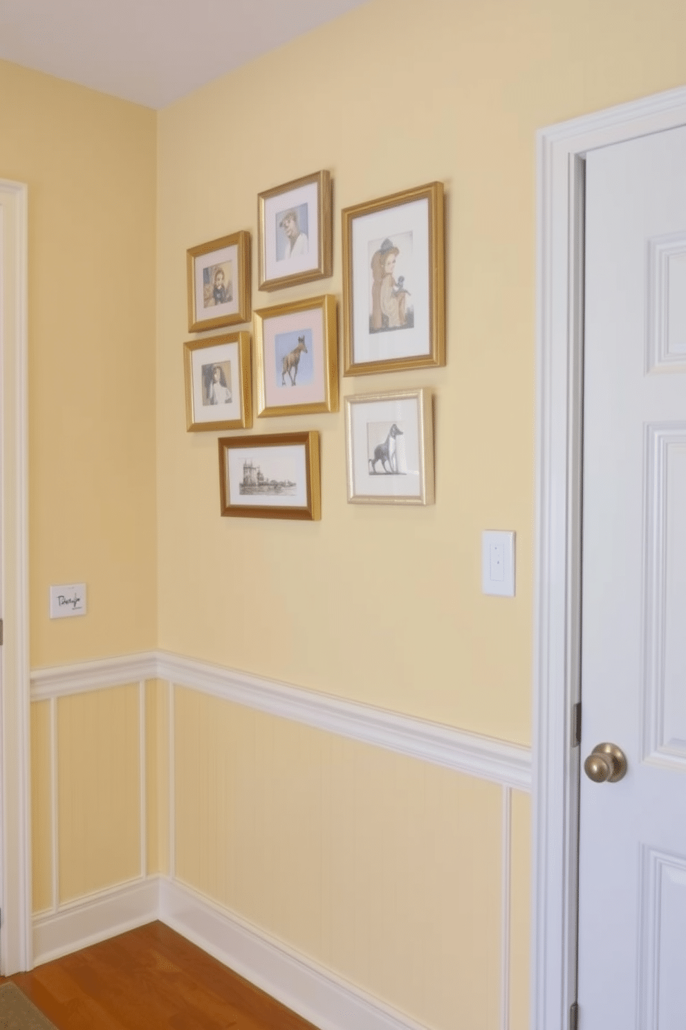 Light yellow wainscoting adorns the walls of a bright and inviting foyer, creating a warm and welcoming atmosphere. Above the wainscoting, a collection of framed artwork in soft pastel hues adds a touch of elegance and personality to the space.